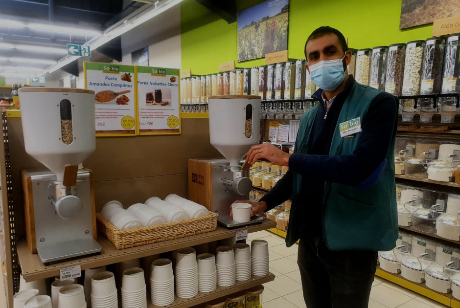 L'employé d'un supermarché fait une démonstration de l'utilisation du moulin à oléagineux de supernutural.
